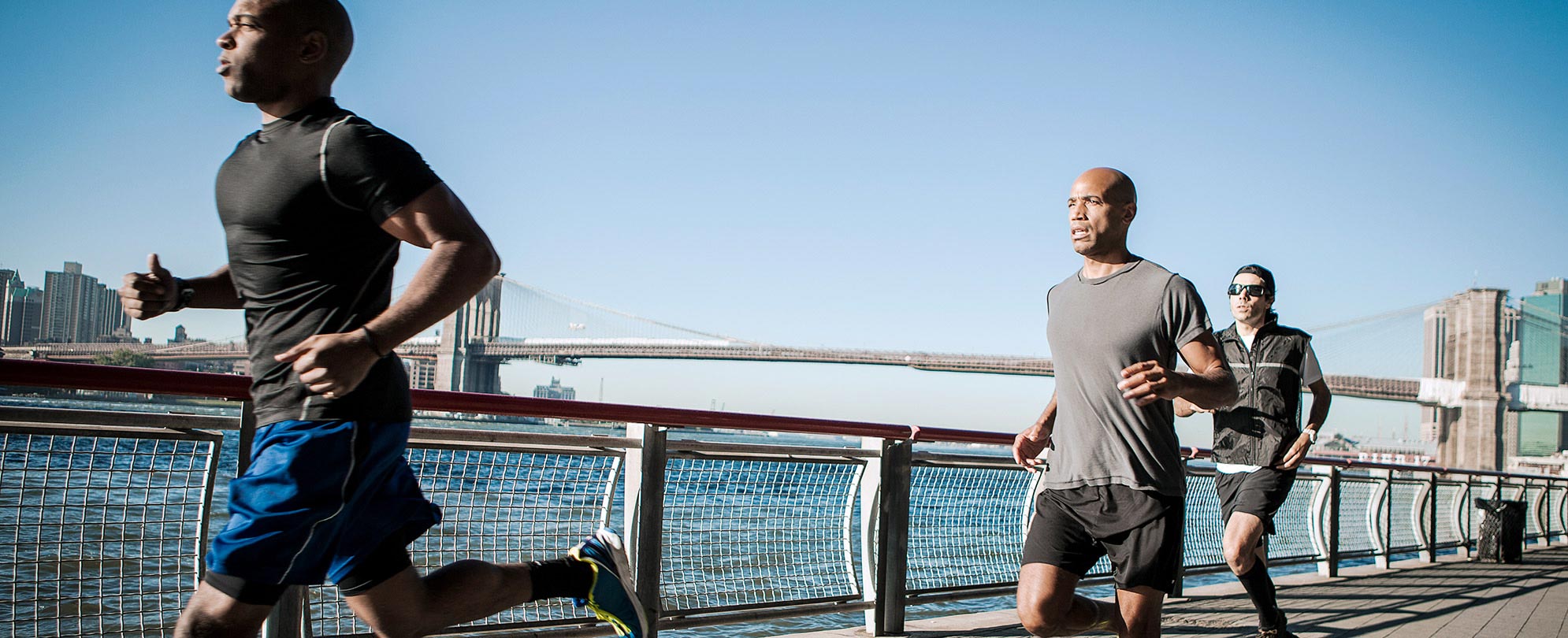 3 joggers on a waterfront boardwalk