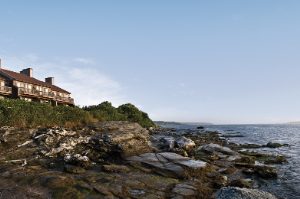 The exterior of Club Wyndham Newport Overlook, a timeshare resort in Newport, RI on a rocky shoreline.