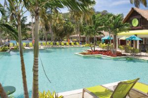 Bright green pool chairs and palms surround the pool and tiki bar of Margaritaville Vacation Club by Wyndham - St. Thomas.