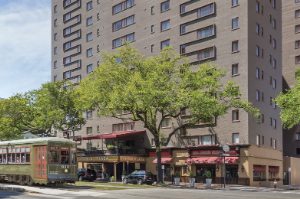 The exterior of the Avenue Plaza timeshare resort in New Orleans, Louisiana with a trolly car in front. 