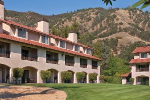 The exterior of a resort in front of a small mountain range at WorldMark Clear Lake.